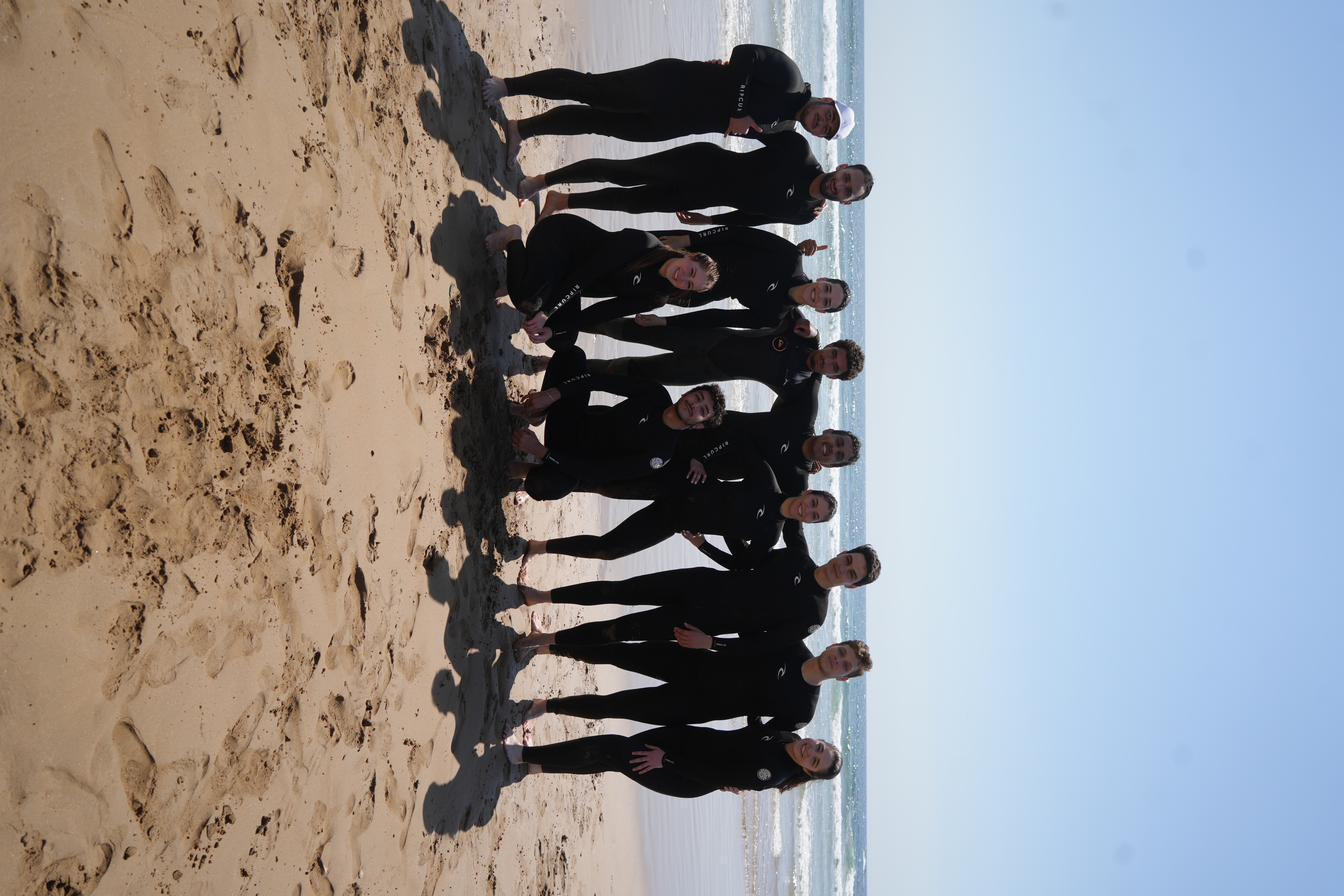 Group of surfers giving thumbs up on the beach