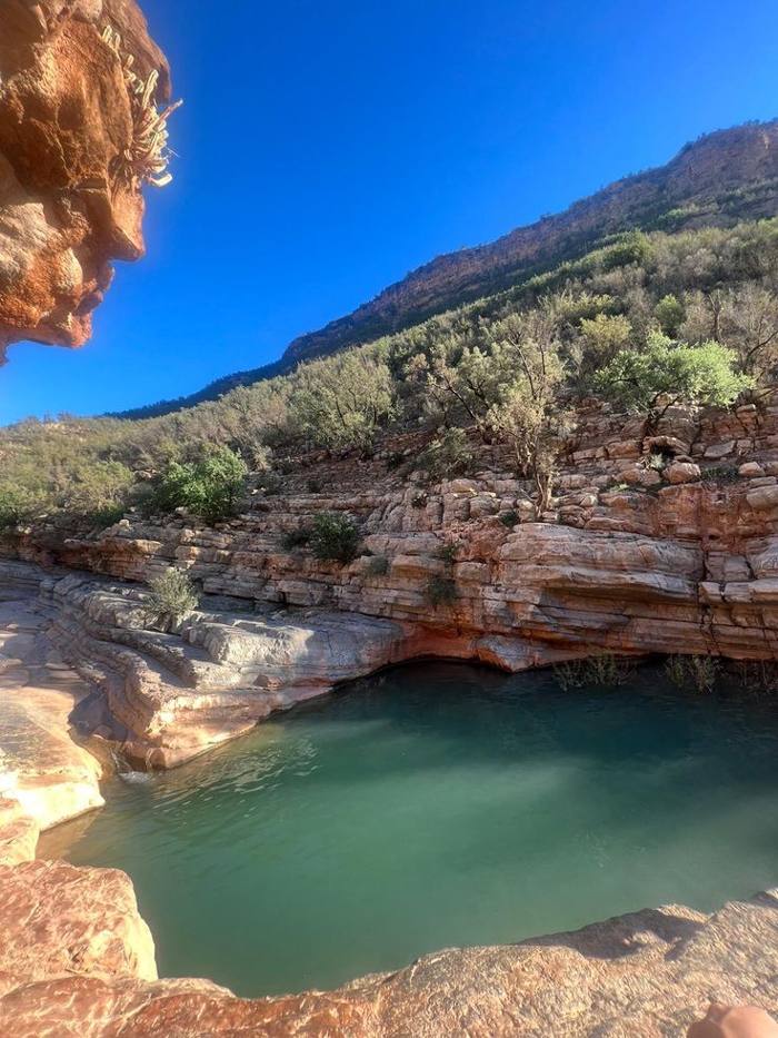 Green pool below layered rock